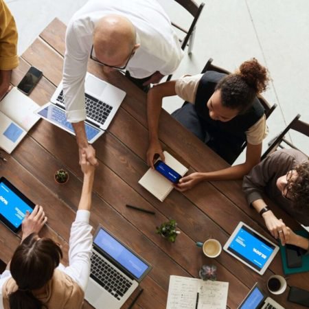 Employees around a table, one shaking hands.
